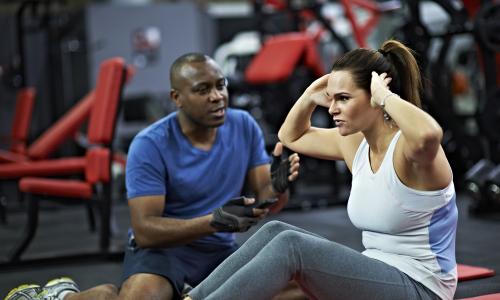 A personal trainer guides a woman doing sit ups