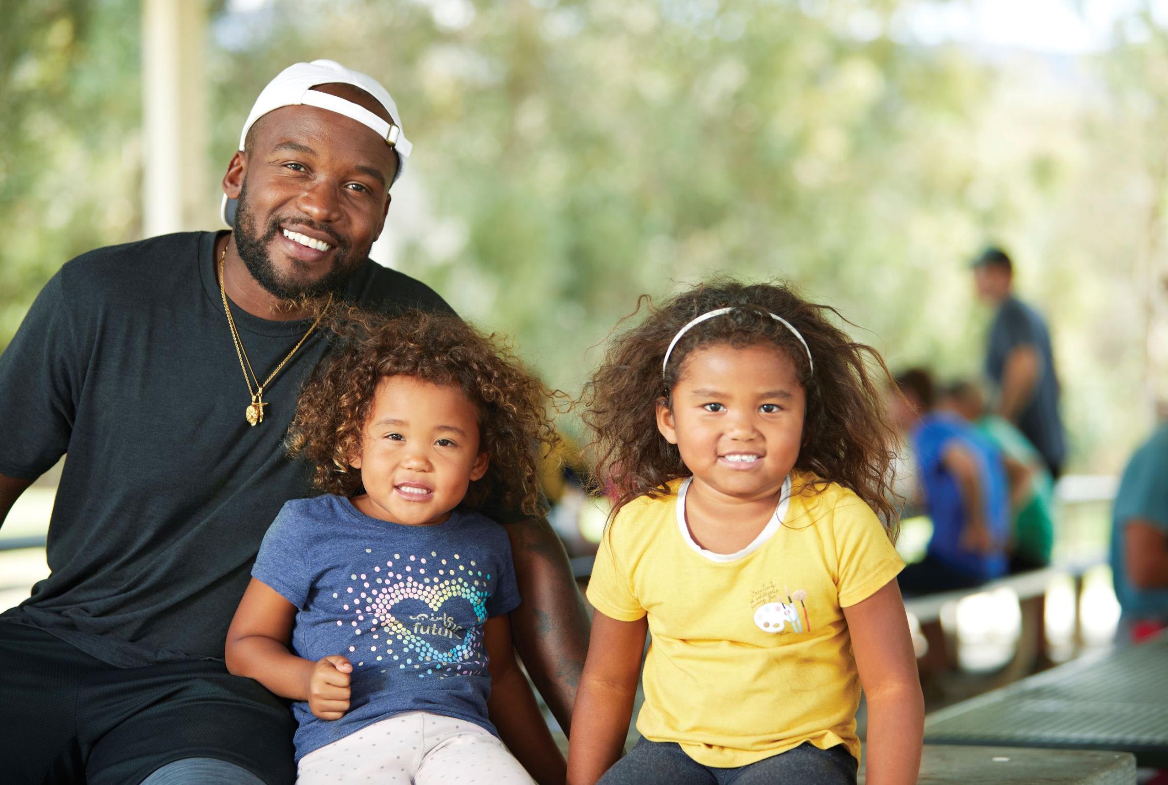 father with his two daughters smiling at a picnic table