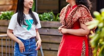 2 women laughing, one in Y t-shirt and jeans, other woman wearing traditional culture-specific clothing