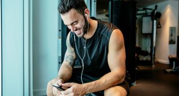 Man using his phone on an exercise machine.
