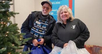 2 YMCA Staff members carrying bags of Christmas presents for donation.